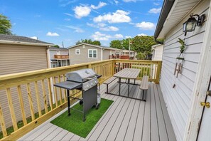 A deck with a grill and picnic table, surrounded by a wooden fence. - SLEEPS 10!  3 bedrms/3 baths/Pier House. One Golf Cart incl. 2nd Cart available (Garden City)