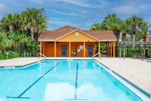 Ein Swimmingpool mit überdachtem Bereich und Palmen im Hintergrund.
