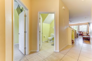 Stylish hallway leads to a bathroom and dining area with a table and chairs.