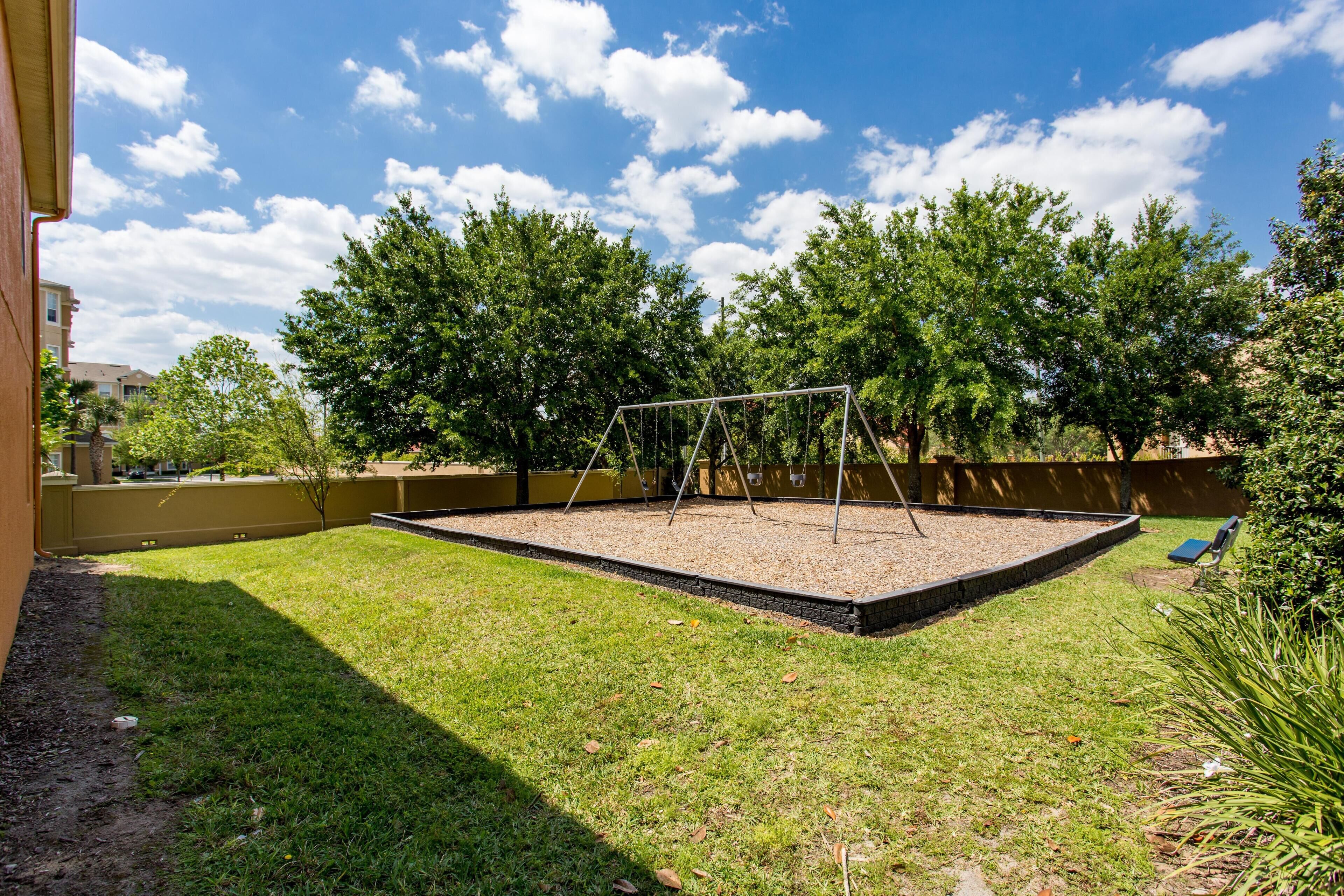 Ein Garten mit Schaukel, einem kleinen Gartenbereich und Blick auf Bäume und Gebäude.