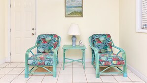 A room with two matching teal chairs, a small table with a lamp, and a door.