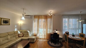 A living room with a sofa, a coffee table, a dining table with chairs, and a fireplace. - Anita Tour As / Central 1BR App, free garage, AC, Wi-Fi, 7min walk from old town (Ljubljana)