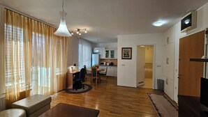 A modern living room with a dining area, wooden flooring, and a kitchen in the background. - Anita Tour As / Central 1BR App, free garage, AC, Wi-Fi, 7min walk from old town (Ljubljana)