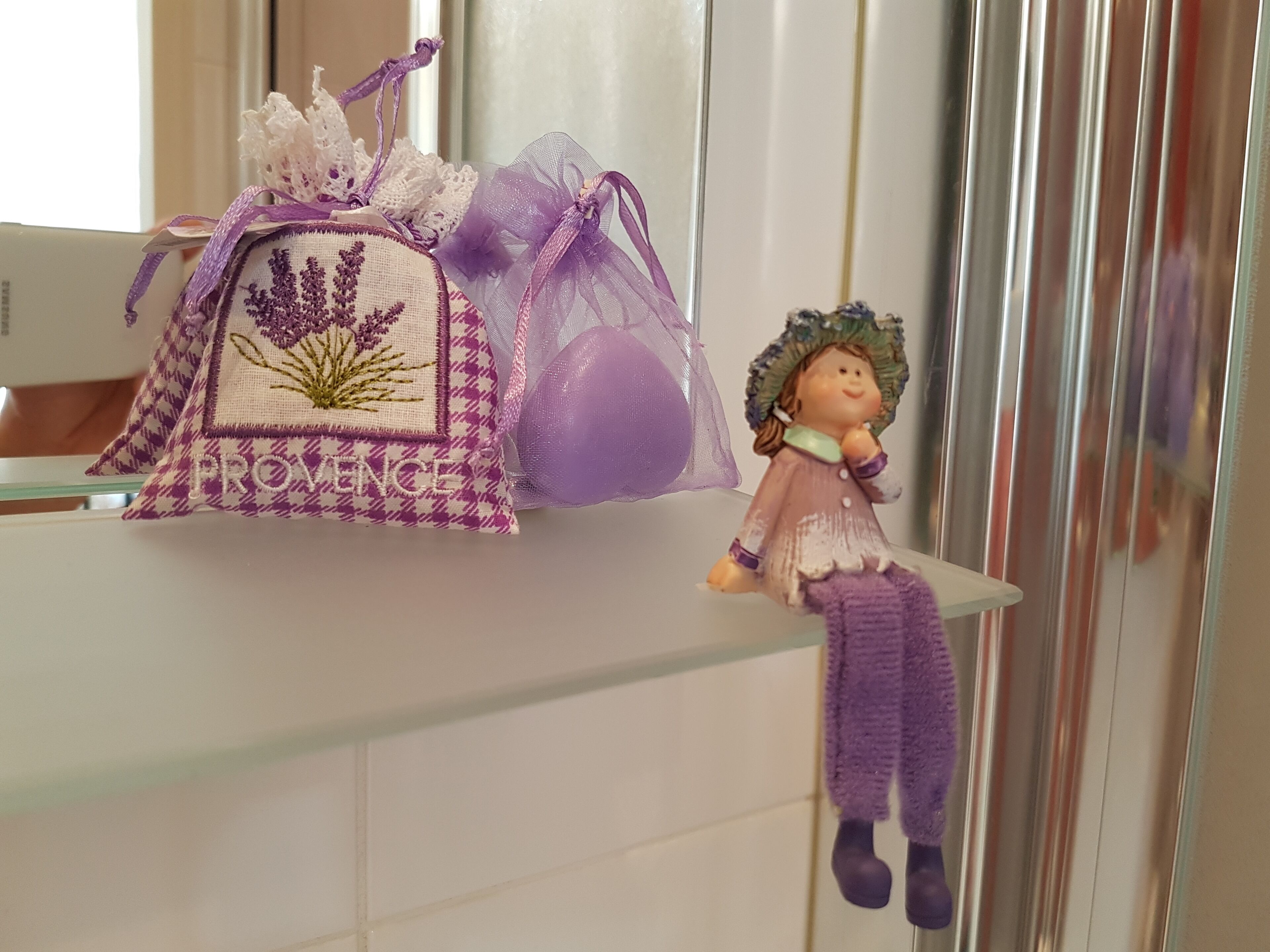 A shelf with a purple and white embroidered bag and a figurine.