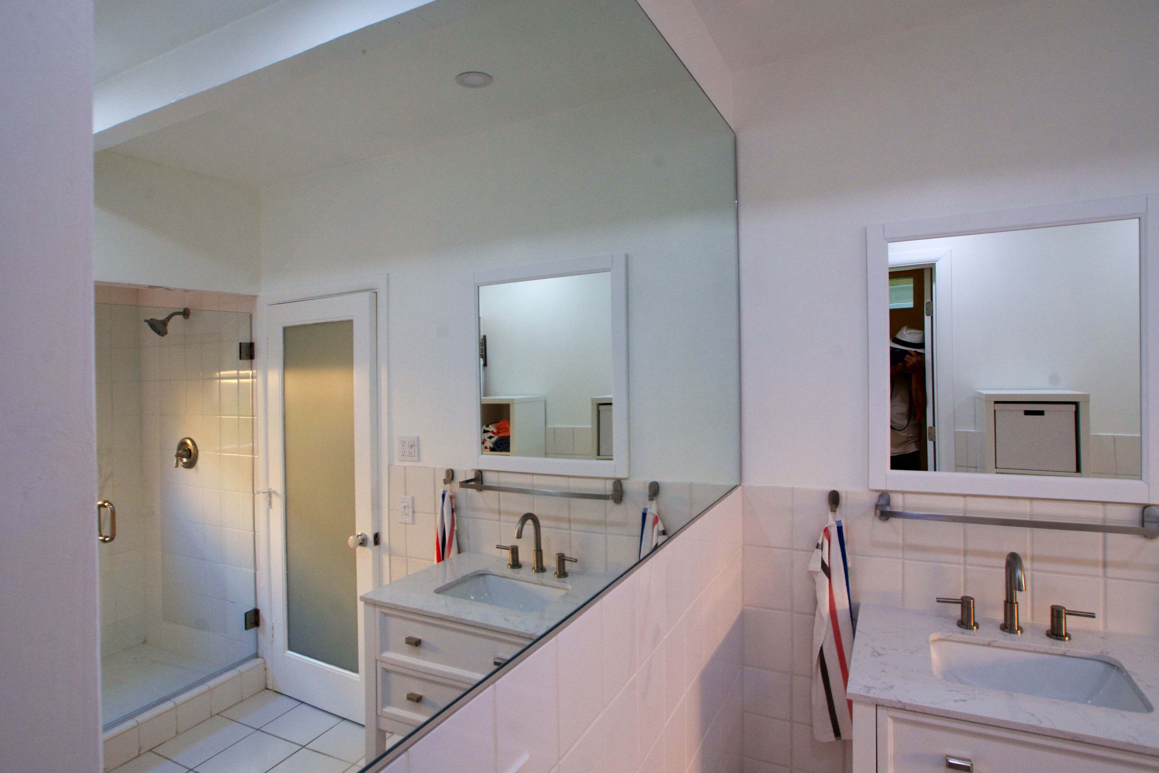 A modern bathroom with a glass shower enclosure, a double sink vanity, and a mirror above the sink.