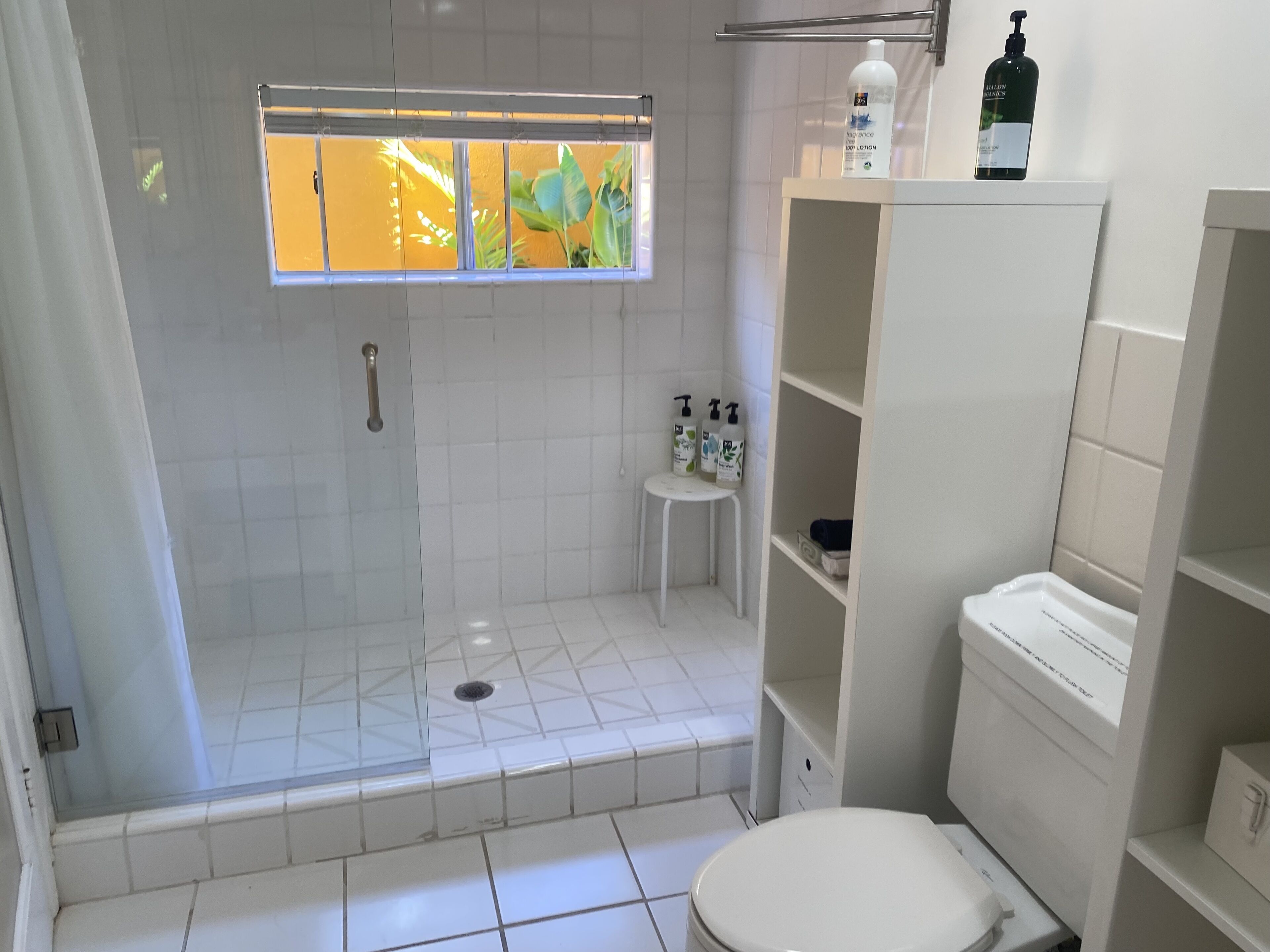 Ein Badezimmer mit Dusche, Toilette und Ablagen für Toilettenartikel.