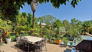 An outdoor patio with a wooden deck, metal chairs, a table, and a barbecue grill. - Corvah House, Beautiful Corvah House circa 1860, restored and beaming with grandeur and comfort (Castlemaine)
