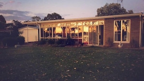 A single-story house with a large front porch, a garage, and a fenced yard. - Foxy Lodge - Lakeside getaway (Nagambie)