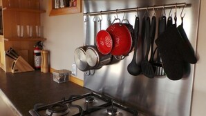 A kitchen with stainless steel appliances, a gas stove, and pots hanging on a rack. - Beautiful Waterview Studio (Ngunguru)