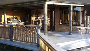 A wooden deck with outdoor seating and a grill area. - Beautiful Waterview Studio (Ngunguru)