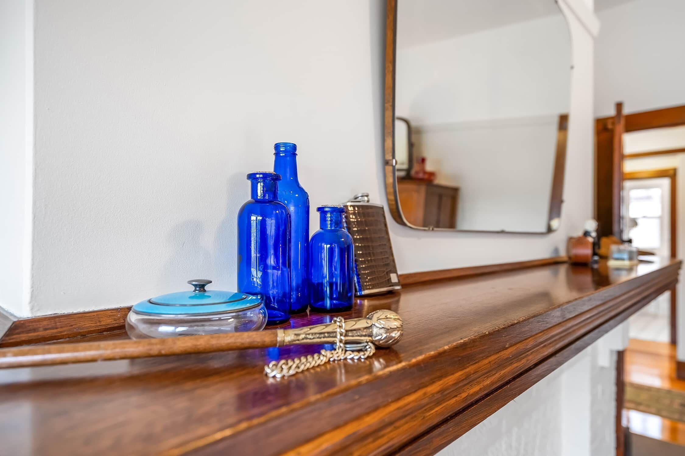 A wooden counter with blue bottles, a clear container, and a decorative item.