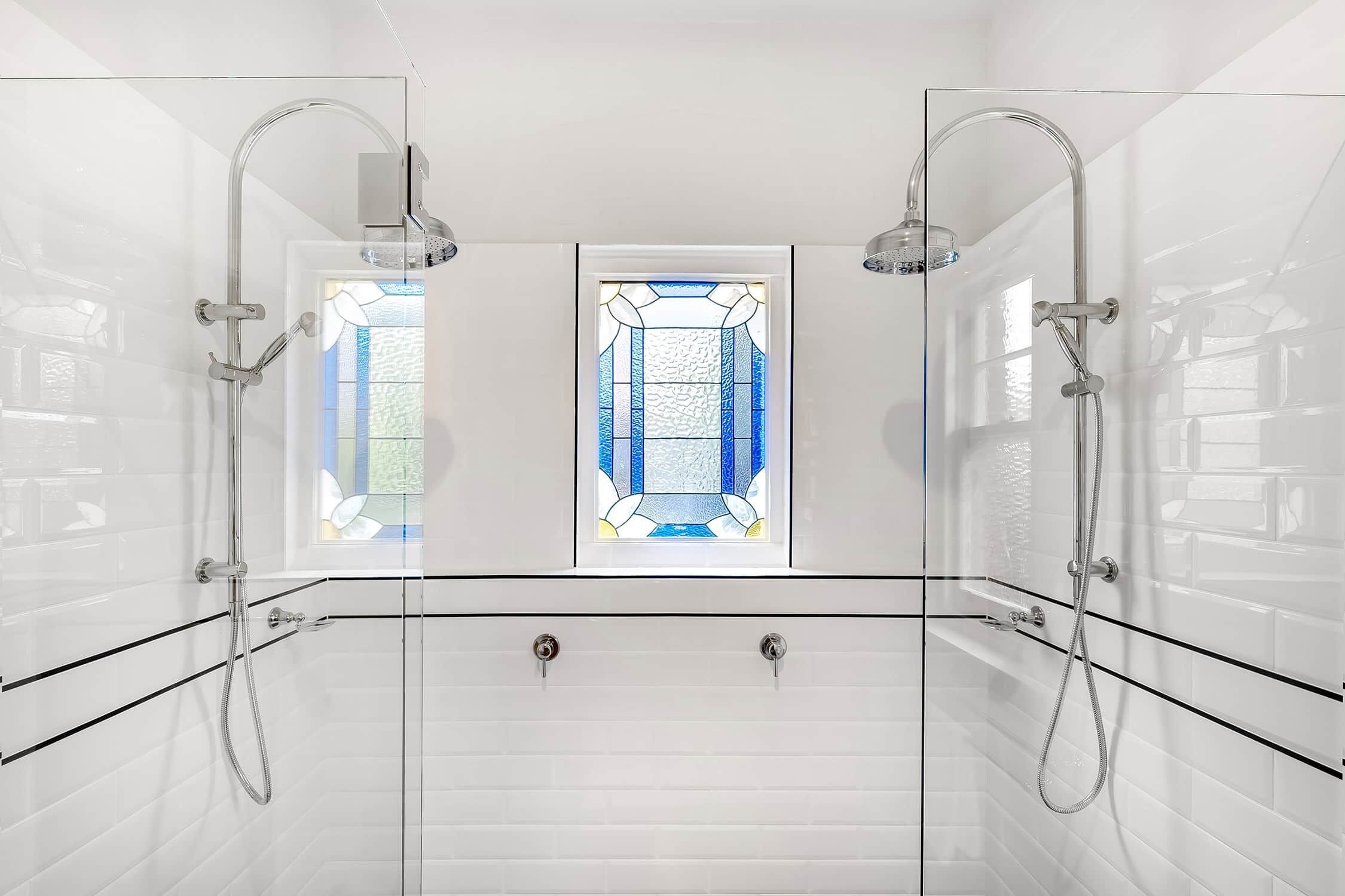 A modern shower with glass doors, a frosted window, and a tiled wall.