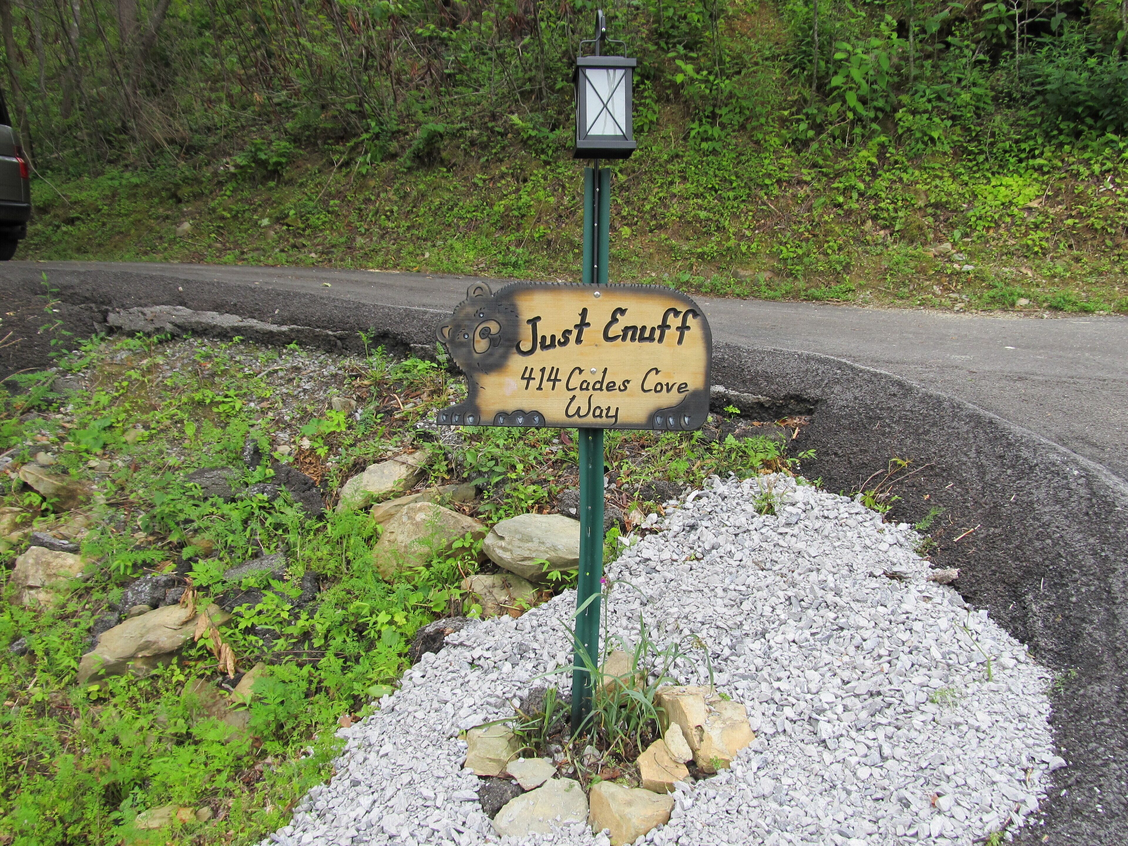 Une enseigne en bois portant l’inscription « Just Enuff 414 Cades Cove Way » et une lanterne placée au-dessus.