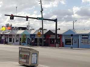 A street view with a traffic light, a street sign for NE 6 AV, and various storefronts including a sushi restaurant and a real estate office.