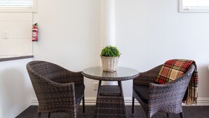 A small, round glass table with wicker chairs, a potted plant, and a plaid throw blanket. - Luxury county guesthouse-continental breakfast supplied/own farm free range eggs (Omarama)
