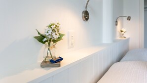 A neatly arranged hotel room with a white bed, a bedside table with a vase of flowers, and wall-mounted lamps. - Luxury county guesthouse-continental breakfast supplied/own farm free range eggs (Omarama)