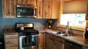 A kitchen with wooden cabinets, stainless steel appliances, a microwave, a kettle, and a dishwasher.