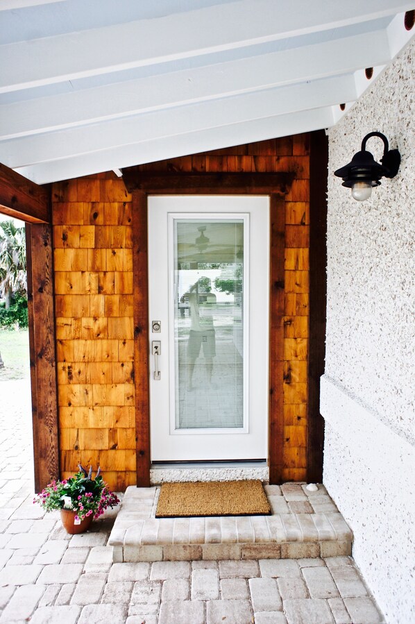 A wooden exterior with a glass door, a potted plant, and a doormat. - 1st Street, Cedar Beach Retreat (Saint Augustine)