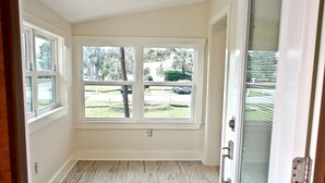 A room with a large window, a sliding glass door, and a tiled floor. - 1st Street, Cedar Beach Retreat (Saint Augustine)