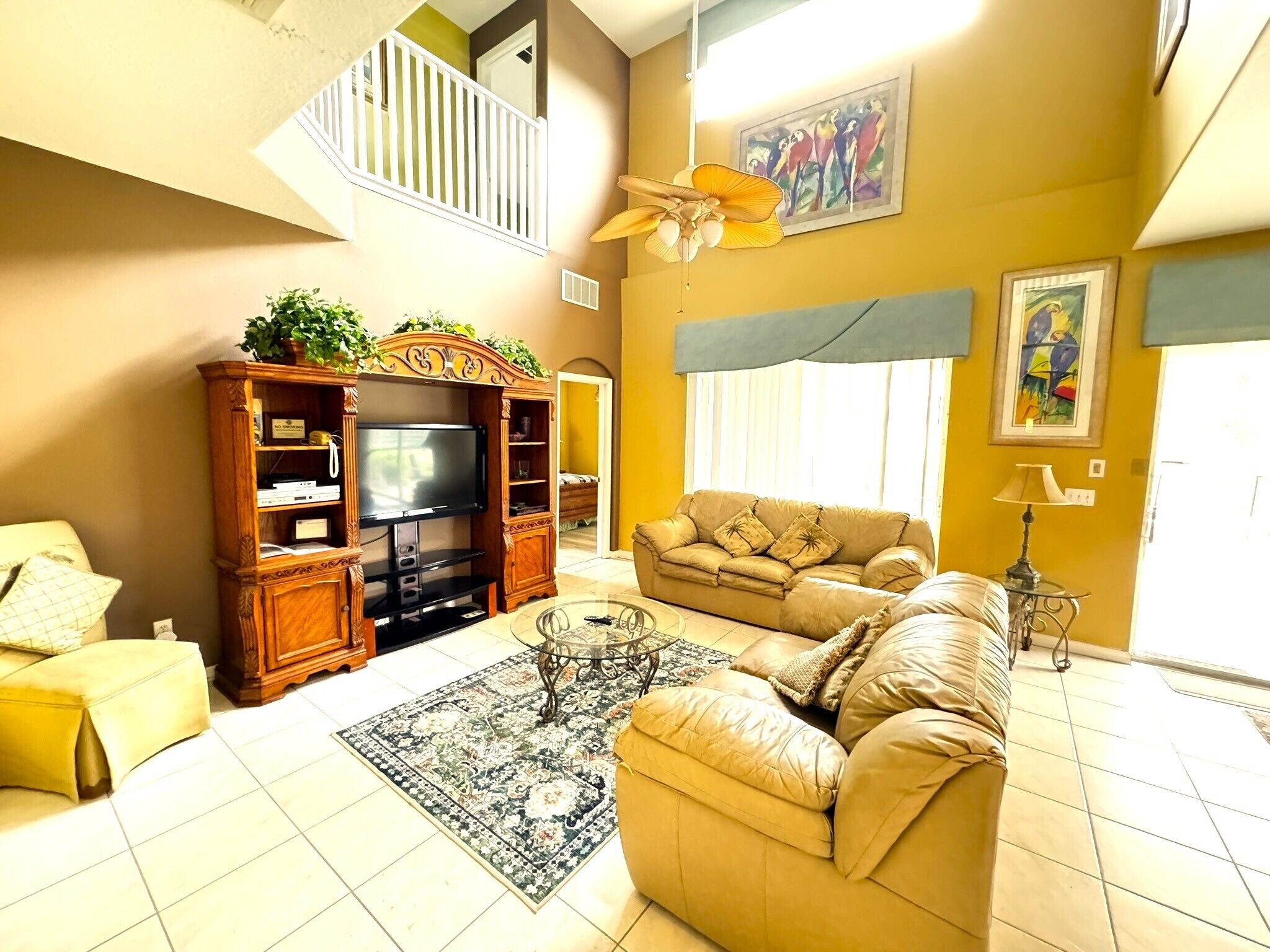 A living room with a sofa, a television, a coffee table, and a decorative ceiling fan.