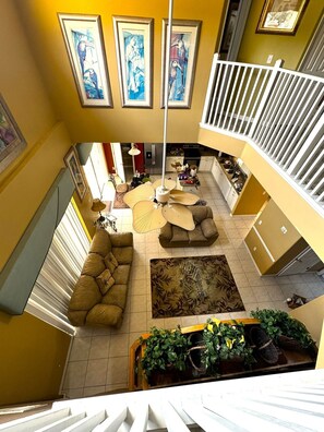 A multi-level living space with a staircase, a sofa, a patterned rug, and a dining area. - Emerald Island Luxury Castle in Kissimmee,7BR/6BA,3mi to Disney Parks (Kissimmee)