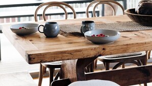 A wooden dining table with bowls, a mug, and a basket. - Cavella South Coast (Culburra Beach)