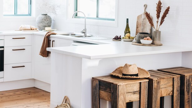 A bright kitchen with white cabinetry, a wooden island, and a rustic wooden bench. - Cavella South Coast (Culburra Beach)