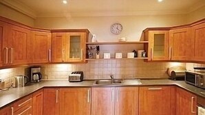 Una cocina con armarios de madera, un microondas, un tostador y un reloj en la pared.