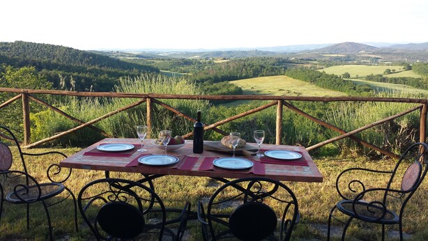 A table set outdoors with a scenic view of rolling hills and a wooden fence. - HILLTOP APARTMENT WITH GREAT WIEW BETWEEN SIENA AND VOLTERRA (Casole D'Elsa)