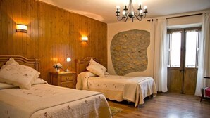 Une chambre avec deux lits, des murs en bois, un mur d’accent en pierre et un lustre.
