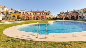 Ein Pool mit kreisförmigem Design, umgeben von einer gepflasterten Fläche und Rasen.