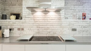 Een keuken met witte bakstenen muren, een roestvrijstalen afzuigkap en een inbouwoven.