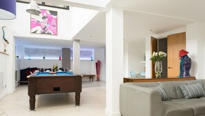 Een moderne woonkamer met een pooltafel, een bank en een groot raam.