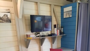 Una habitación acogedora con sofá, un escritorio pequeño y una silla rosa.