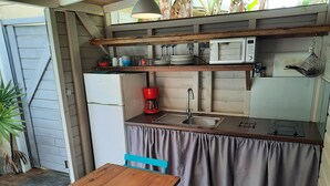 Una cocina compacta con una mesa de madera, un lavamanos, un microondas y una cafetera.