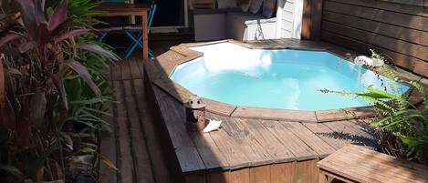 A wooden deck with a hot tub, a covered seating area, and a view of a mountain.
