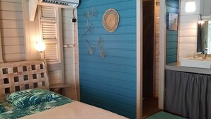 Un dormitorio con cama, cómoda, tocador con espejo y una pared azul decorativa.