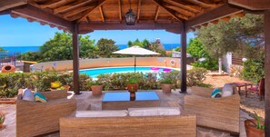 A covered outdoor seating area with wicker furniture, a pool, and a view of the sea. - Cozy Villa, Prime Location, Coral Bay, Large Pool, Billiard, 
Villas for Groups (Paphos (Pafos))