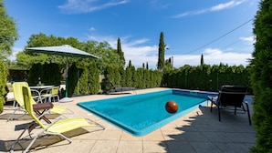 A swimming pool with lounge chairs and a table, surrounded by trees and a clear sky. - House / Villa - Rovinj (Rovinj)