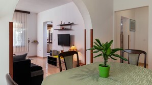 A living room with a TV, a lamp, a dining table with chairs, and a potted plant. - House / Villa - Rovinj (Rovinj)