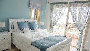 Ein Schlafzimmer mit Bett, Nachttischen und einem Fenster mit Vorhängen.