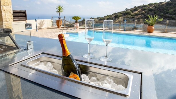 Eine Poolbar mit einer Champagnerflasche, Eiswürfeln und Gläsern auf einem Tisch.