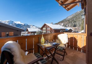 A wooden balcony with a table, chairs, and a bottle of lemon. - Grathoren - Waldbort (car limited village) (Wengen)