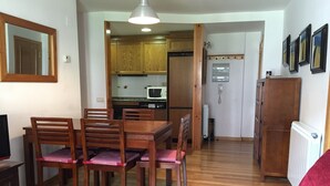 Un comedor con una mesa y sillas de madera, una cocina al fondo y un sofá rojo.