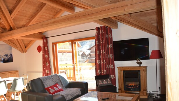 Ein gemütliches Wohnzimmer mit Kamin, einer Couch, einem Couchtisch und einem Fernseher.