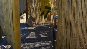 A bamboo fence with a hat hanging on it, a patterned mat on the ground, and a view of mountains in the background. - The African House, rural getaway between Ronda and Málaga (Tolox)