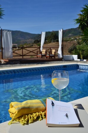 A poolside setting with a glass of white wine, a book, and a yellow towel. - The African House, rural getaway between Ronda and Málaga (Tolox)