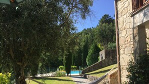 Un edificio de piedra con una hamaca y una piscina al fondo.