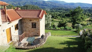 Un edificio de piedra con techo de tejas, un pequeño balcón y una mesa en el exterior.