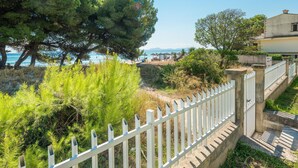 Une propriété située sur la côte, avec une clôture blanche, des arbres et une vue sur la mer.